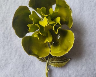 Peut inclure: Une broche en forme de fleur avec des pétales superposés et ondulés dans une finition émaillée vert chartreuse vif. La pièce florale présente une tige fine et incurvée avec une feuille dentelée, le tout dans un ton vert assorti.