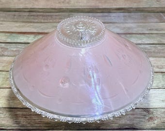 May include: A vintage pink glass lampshade with a clear, decorative rim and a detailed, etched pattern. The shade has a rounded, bowl-like shape and is made of iridescent glass. The design features floral and geometric elements.
