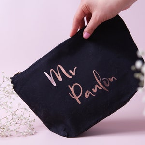 May include: A black canvas zippered pouch with a rose gold inscription that reads "Mr. Panlon".