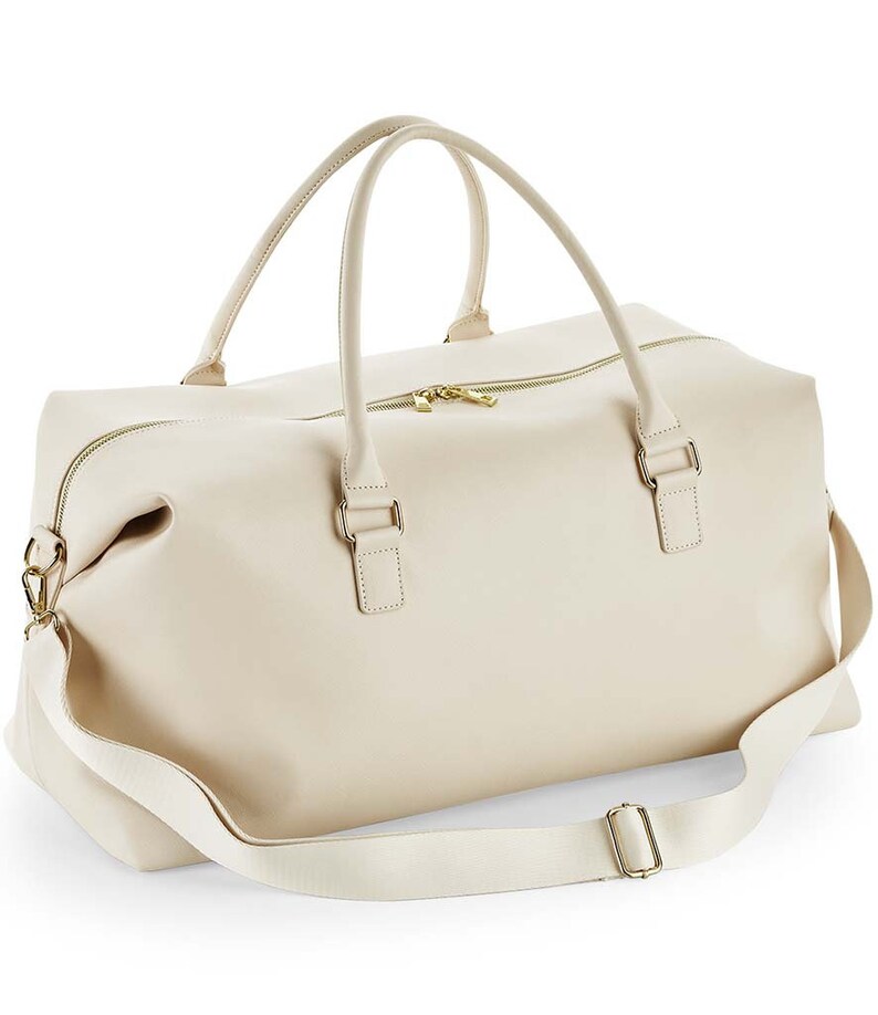 May include: A cream-colored leather weekender bag with a top zipper closure, two top handles, and a detachable shoulder strap.