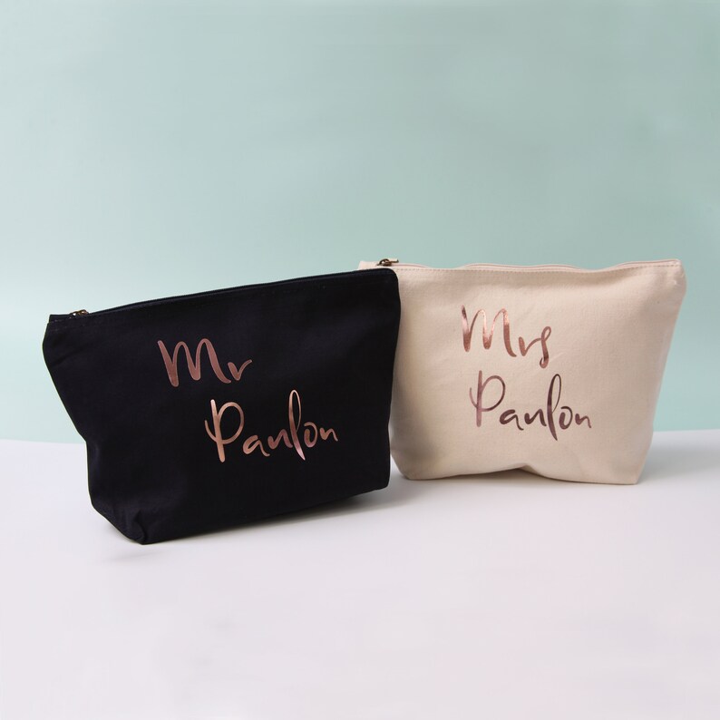 May include: Two canvas zippered pouches, one black and one beige, with the words "Mr. Paulson" and "Mrs. Paulson" in rose gold lettering.