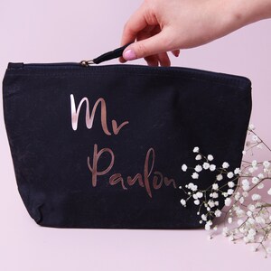 May include: A black canvas zippered pouch with a rose gold inscription that reads "Mr. Pamlon".