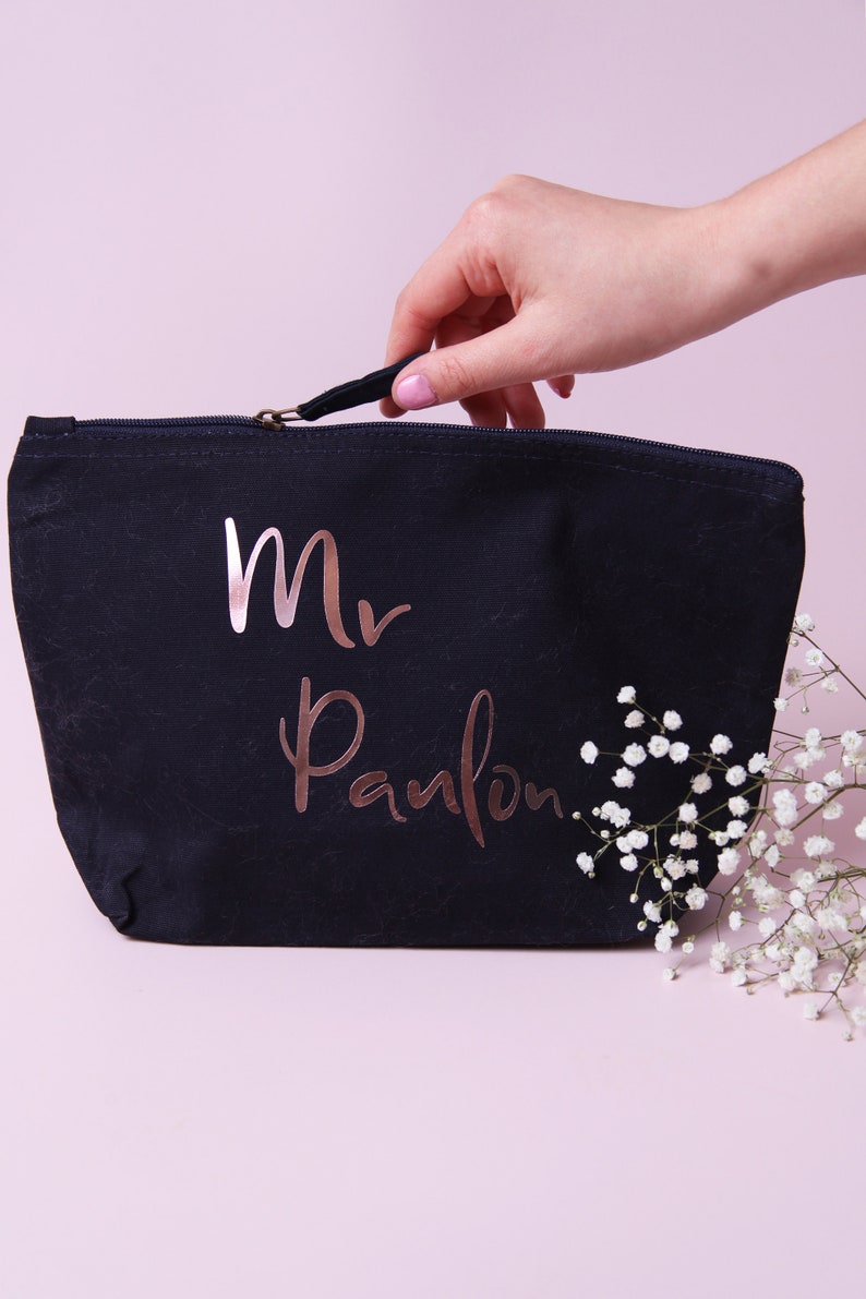 May include: A black canvas zippered pouch with a rose gold inscription that reads "Mr. Pamlon".