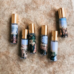 Puede incluir: Siete botellas de rodillo doradas con diferentes etiquetas. Las etiquetas tienen un tema de naturaleza e incluyen las palabras "Respira", "Concéntrate", "Duerme", "Energía", "Bienestar", "Moony" y "Dreamy".