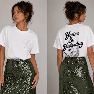 Pode incluir: Uma t-shirt branca de manga curta com um pequeno gráfico de interruptor de luz no peito e o texto "You're So Yesterday" em letra preta nas costas, combinada com uma saia de lantejoulas verde-escura com uma superfície brilhante.