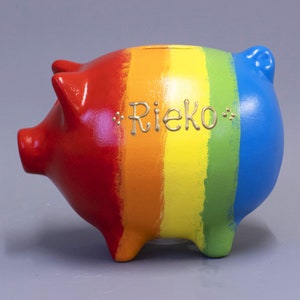 May include: A red, orange, yellow, green and blue piggy bank with the name "Rieko" written in gold lettering.