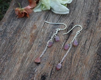 May include: A pair of silver dangle earrings with pink and green gemstone drops. The earrings feature a delicate chain design and are ideal for adding a touch of colour to any outfit.