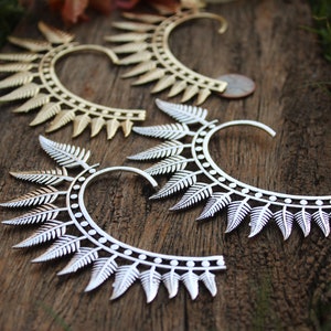 Könnte beinhalten: Drei silberne und goldene Ohrringe mit einem Farnblatt-Design. Die Ohrringe sind aus Metall und haben ein zartes, filigranes Design.