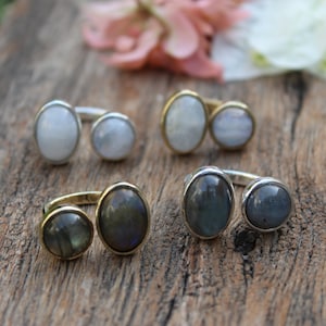 May include: Four silver and gold rings with two oval-shaped gemstones. The rings are on a wooden surface.