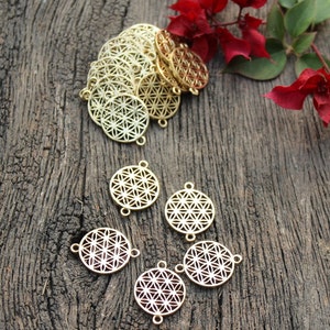 Puede incluir: Un conjunto de dijes de metal de color dorado con un diseño de flor de la vida. Los dijes tienen dos anillos de salto para sujetarlos a joyas u otras manualidades.