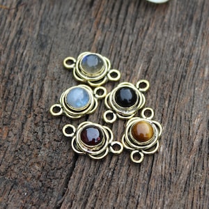 May include: Six gold-toned metal charms with different colored gemstones. Each charm has a double loop for attaching to jewelry.
