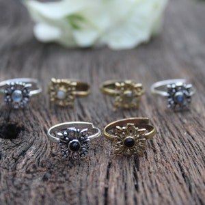 May include: Six silver and gold toe rings with decorative floral designs and gemstone accents. The rings feature a variety of gemstones, including moonstone and black onyx.