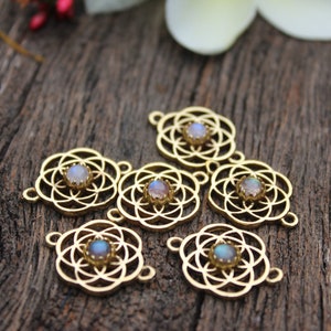 May include: Six gold-toned metal charms with a geometric design and a clear iridescent stone in the center. The charms are arranged on a wooden surface.