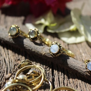 May include: A set of gold rings with different colored gemstones. The rings are on a wooden surface.