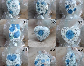 May include: Nine different cabochon gemstones, each with a unique shape and pattern of blue and white. The gemstones are arranged in a grid of three rows and three columns. The gemstones are all approximately the same size and are all set in a clear resin.