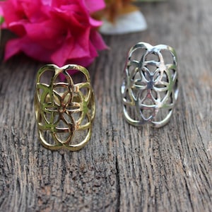 May include: Two silver rings with a geometric flower design. The rings are on a wooden surface.