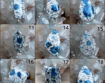 May include: Nineteen cabochon gemstones, each with a unique shape and pattern of blue and white. The stones are arranged in a grid of three rows and six columns. The stones are labeled with numbers 10 through 18.