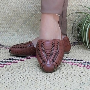 May include: Brown leather sandals with a woven design. The sandals have a pointed toe and a low heel.