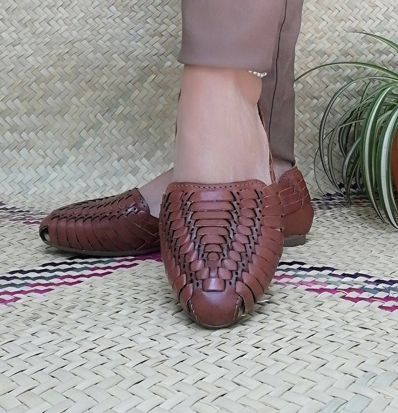 May include: Brown leather sandals with a woven design. The sandals have a pointed toe and a low heel.