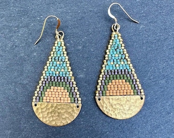 May include: A pair of handcrafted earrings with a beaded design. The earrings feature a teardrop shape with a hammered gold-tone metal base. The beaded section showcases a pattern of turquoise, green, purple, and peach colors, creating a unique accessory.
