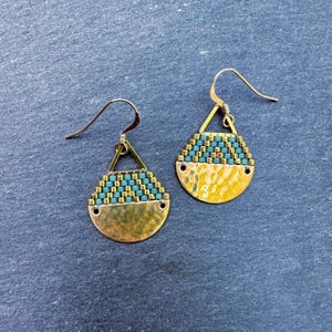 May include: A pair of gold and teal earrings with a hammered metal disc and beaded design.