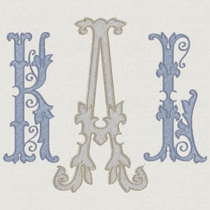 Könnte beinhalten: Gesticktes Monogramm mit den Buchstaben K, A und L. Die Buchstaben sind in einem dekorativen, verzierten Stil mit einem hellblauen und beigen Farbschema gehalten. Der Hintergrund ist ein hellbeiger Stoff.