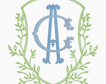 Op de afbeelding: Een lichtblauw monogram met de letters "A" en "C" verweven, geplaatst in een witte schildvorm. Het schild wordt omlijst door een dubbel gevoerde groene rand en omringd door een groene bladerkrans, wat een decoratief embleem creëert.