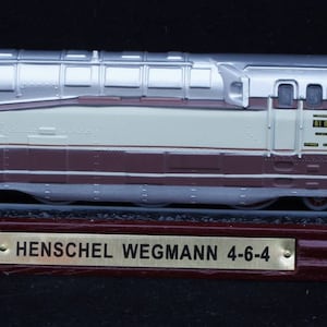 May include: A silver and brown model train locomotive with a Henschel Wegmann 4-6-4 label on a wooden base.