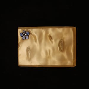 May include: A small, rectangular, cream-colored box with a blue flower design on the top.