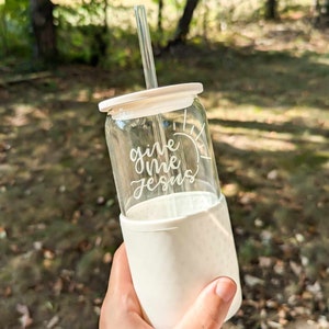 May include: A white glass tumbler with a white lid and a clear straw. The tumbler has the words "give me jesus" written on it.