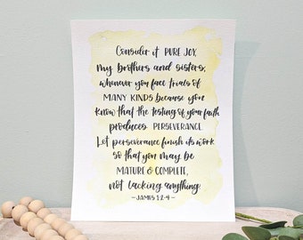 May include: A watercolor print with the text "Consider it PURE JOY" and a Bible verse. The print is on a white background with yellow watercolor accents. A wooden bead garland and greenery are in the foreground.