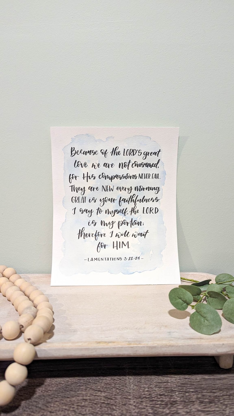 May include: A watercolor print with a blue and white background featuring a bible verse from Lamentations 3:22-24. The verse reads "Because of the LORD's great love we are not consumed, for His compassions NEVER FAIL. They are NEW every morning GREAT is your faithfulness I say to myself, the LORD is my portion: therefore I will wait for HIM -LAMENTATIONS 3:22-24- "
