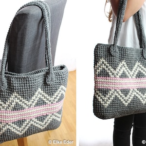Pode incluir: Uma bolsa tote de crochet cinza com padrões geométricos brancos e rosa. A bolsa tem duas alças longas e é mostrada pendurada em uma cadeira e sendo segurada por uma pessoa.