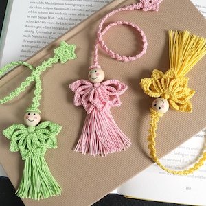 以下が含まれることがあります： 緑、ピンク、黄色の手作りのかぎ針編みのブックマーク3つ。各ブックマークは、木製のビーズの顔とタッセルが特徴です。緑のブックマークには星、ピンクには円、黄色には花があります。