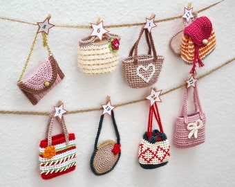 May include: A collection of 10 crocheted mini bags hanging from a string with clothes pegs and star-shaped tags. The bags are in various colours and designs, including pink, brown, white, red, orange, and green.