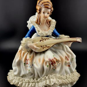 Vintage Victorian Lady playing a Mandolin while seated wearing dress with lace trim on the bottom
