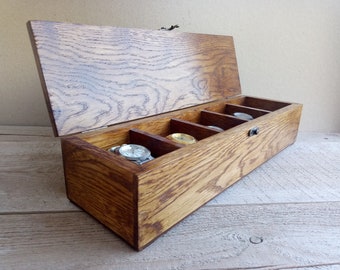 May include: A wooden watch box with a hinged lid and six compartments for storing watches. The box is made of dark brown wood with a natural wood grain pattern.