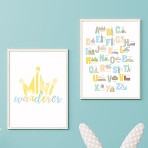 May include: Two framed prints, one with a yellow crown and the text "mini wanderer" and the other with a colourful alphabet with each letter illustrated with a landmark.