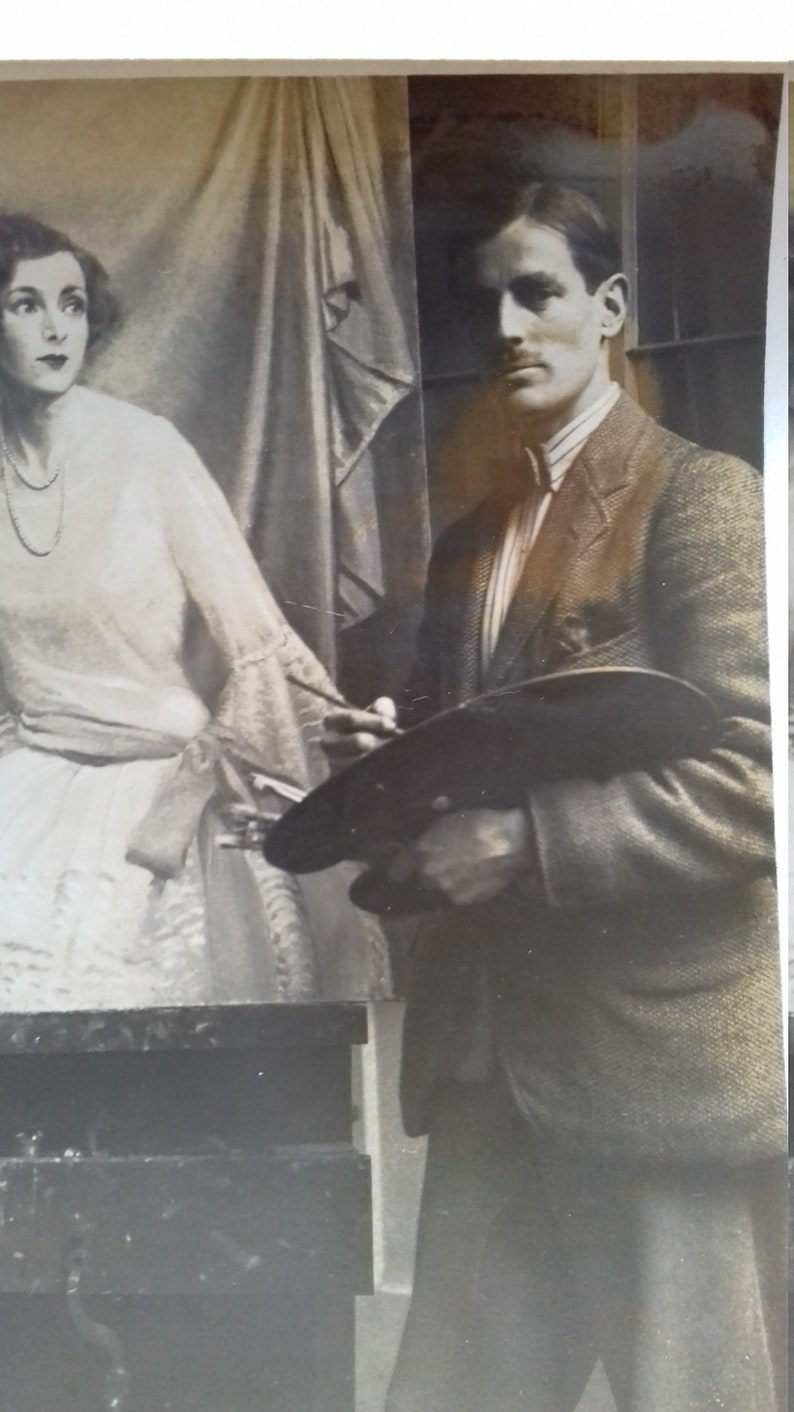 Puede incluir: Una fotograf&iacute;a en blanco y negro de un hombre sosteniendo una paleta de pintura y un pincel, de pie junto a una mujer con un vestido blanco. El hombre lleva una chaqueta de traje y una camisa con cuello. La mujer lleva un vestido blanco con un lazo en la cintura.