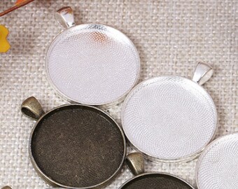 May include: Six round metal pendant trays with a silver and bronze finish. The trays have a smooth surface and are perfect for crafting jewelry.