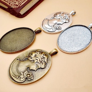 May include: Four oval-shaped metal pendants with a cameo design. Two pendants are silver with a smooth surface and two pendants are bronze with a textured surface. Each pendant has a loop at the top for attaching a chain.
