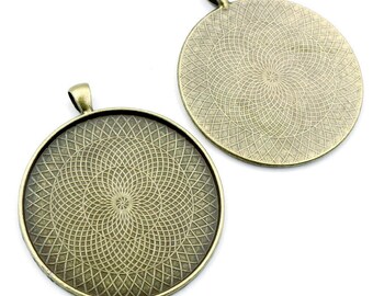 Op de afbeelding: Twee ronde, bronzen metalen hanger-schalen met een decoratief, geometrisch patroon. De schalen hebben een lus aan de bovenkant om op te hangen.