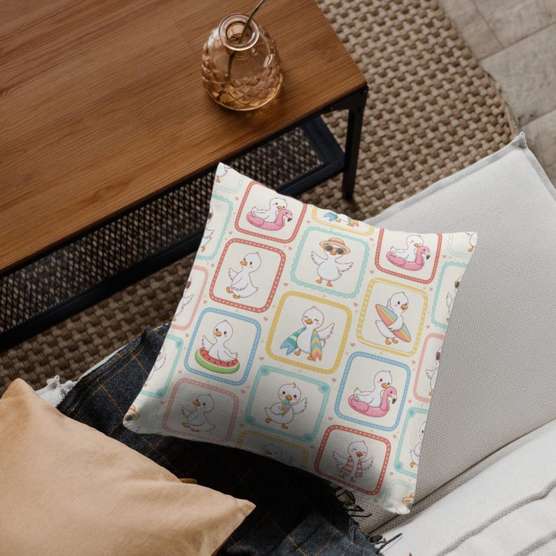 May include: A square throw cushion featuring a repeating pattern of white cartoon ducks in various summer activities, including wearing sunglasses, holding surfboards, and floating on inflatable rings, set within colourful rounded square frames.