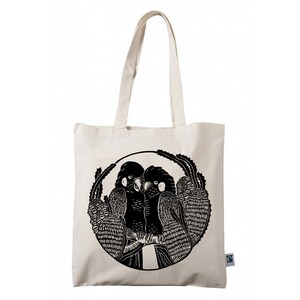 May include: A white canvas tote bag with black handles and a black and white illustration of two parrots in a circle on the front. The bag has a small green tag with the word "organic" on it.