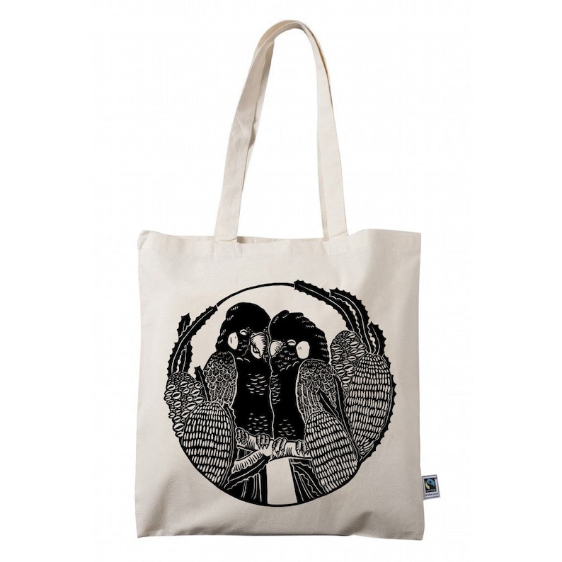 May include: A white canvas tote bag with black handles and a black and white illustration of two parrots in a circle on the front. The bag has a small green tag with the word "organic" on it.