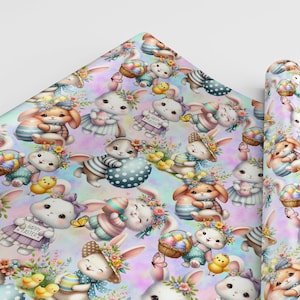 以下が含まれることがあります： パステルピンクとブルーの包装紙で、イースターエッグとヒヨコを持ったウサギが繰り返し描かれています。ウサギは花柄のヘッドバンドを付けており、中には帽子をかぶっているものもいます。ウサギの1匹が持っている看板には「ハッピーイースター」と書かれています。