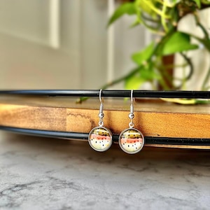 May include: A pair of silver dangle earrings with round glass charms featuring a colorful trout pattern.