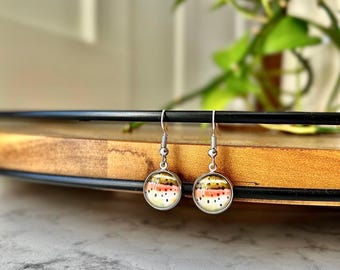 May include: A pair of silver dangle earrings with round glass charms featuring a colorful trout pattern.