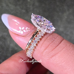 May include: A marquise-cut diamond engagement ring with a halo setting, paired with a diamond band. The rings are gold and feature numerous small, round diamonds. The image includes the text "Skailash Jewels".
