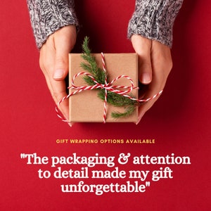 May include: A brown gift box with a red and white ribbon and a sprig of green pine. The box is being held by two hands. The text "GIFT WRAPPING OPTIONS AVAILABLE" and "The packaging & attention to detail made my gift unforgettable" is below the box.